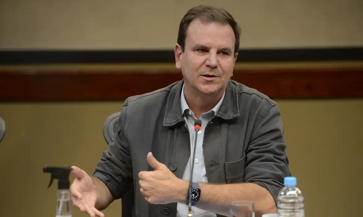 Foto de Eduardo Paes em palanque político com cores do PSD ao fundo, representando sua candidatura ao governo do Rio de Janeiro em 2026