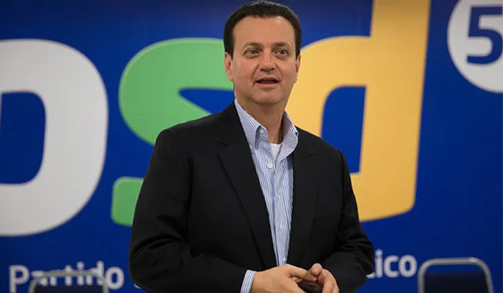 Logo do PSD sobre fundo desfocado do plenário da Câmara dos Deputados, simbolizando a perda de bancada do partido nas eleições de 2026