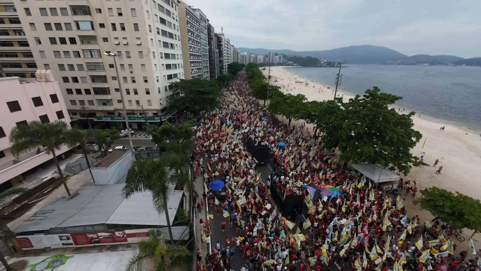 Multidão de apoiadores de Lula reunida na Praia de Icaraí, em Niterói, com faixas e bandeiras vermelhas durante manifestação eleitoral em prol da reeleição presidencial