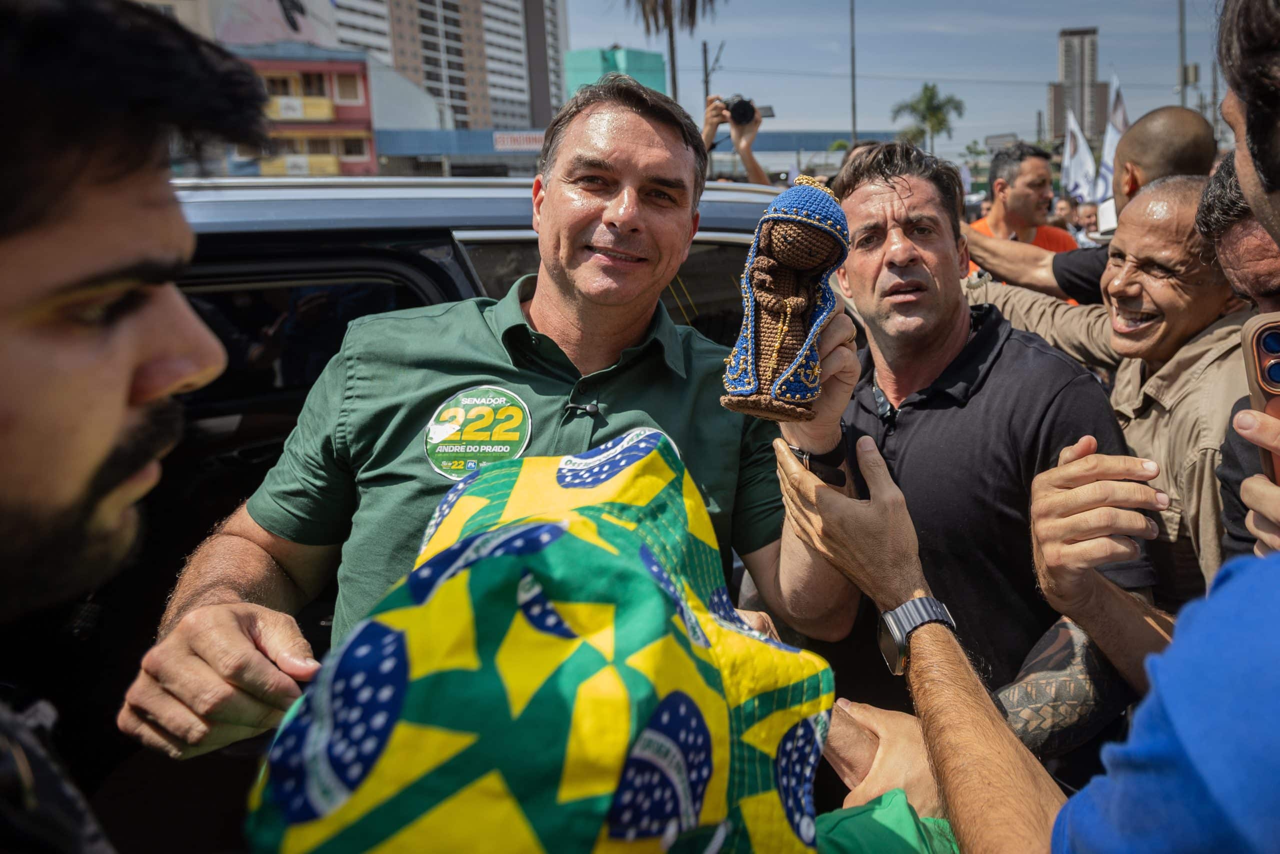 Senador Flávio Bolsonaro em palanque eleitoral exibindo imagens de Nossa Senhora Aparecida durante campanha política