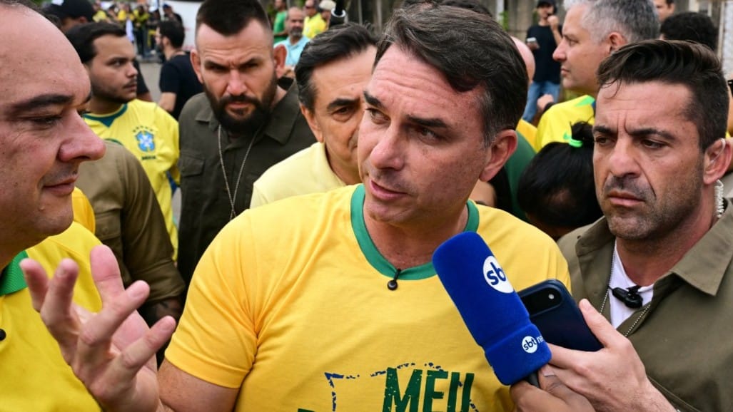 Imagem ilustrativa mostrando Flávio Bolsonaro em contexto político, com referência à pauta da escala de trabalho 5x2 e possível reforma trabalhista oculta no programa do PL