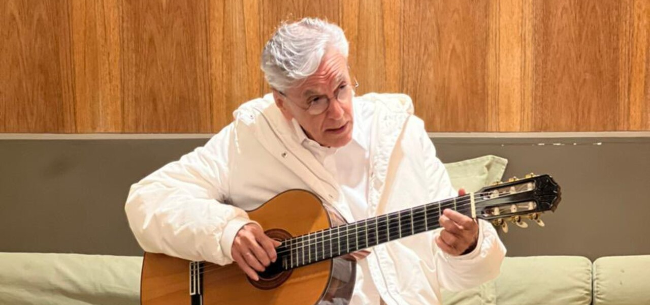 Caetano Veloso em performance ao vivo, com microfone, representando o engajamento artístico em defesa da democracia brasileira