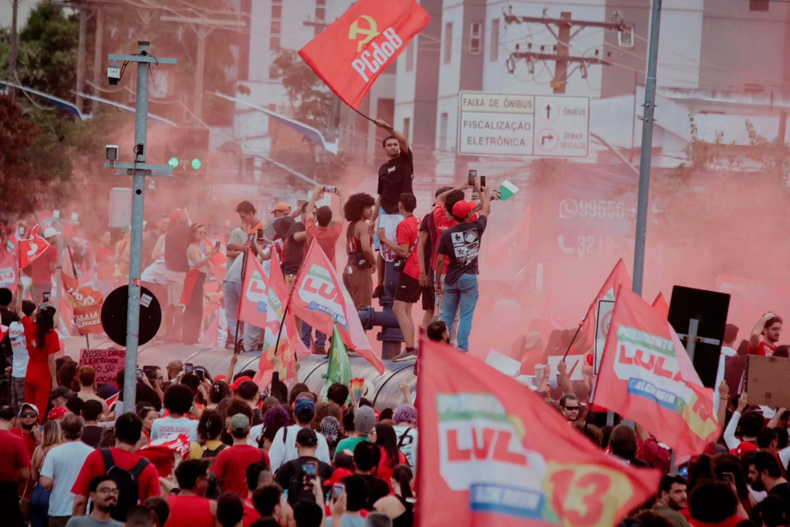 Manifestantes reunidos em praça pública durante ato de apoio à candidatura de Lula ao segundo turno presidencial, com faixas e bandeiras de movimentos sociais e partidos aliados.