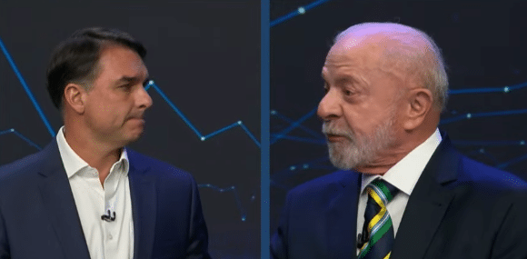 Flávio Bolsonaro em palco de debate presidencial na Band apresentando proposta sobre compra de dívidas de famílias brasileiras
